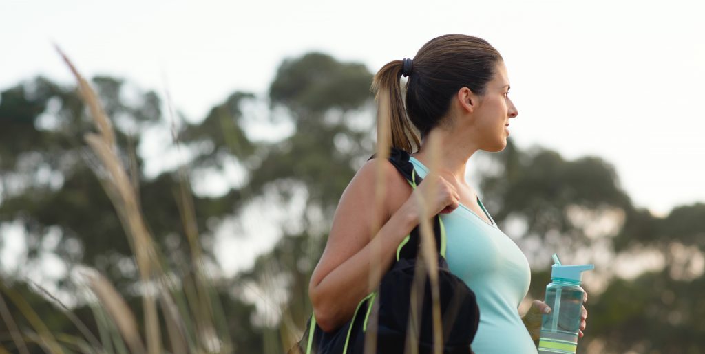 Fitness pregnant woman drinking water after outdoor workout - Simply Gym